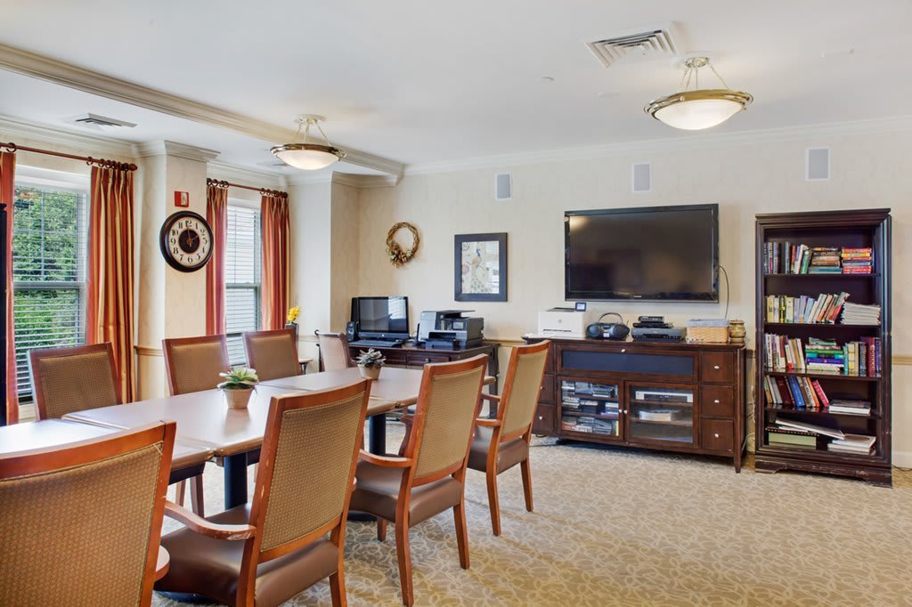 A well-equipped conference room with a large table, chairs, a television, and computers.