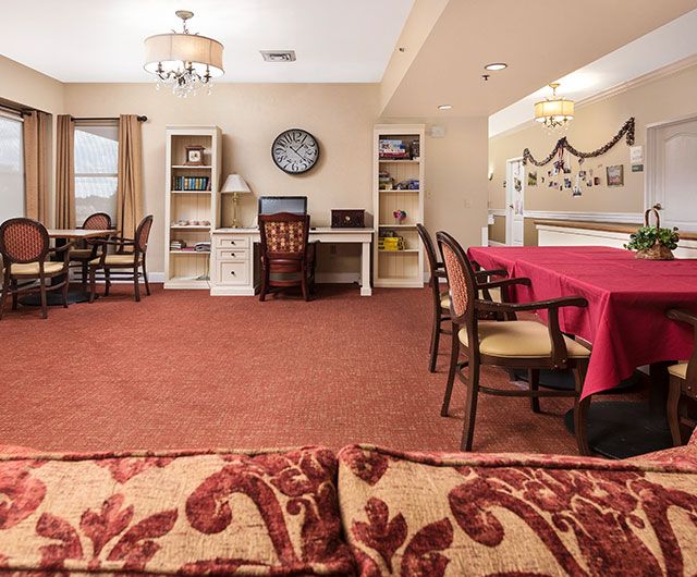 A cozy living and dining area with red carpeting, featuring comfortable furniture and homely decorations.
