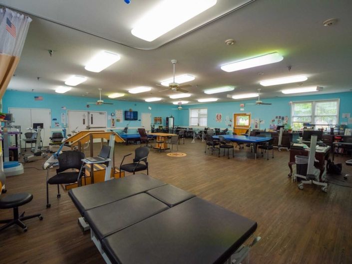 A spacious physical therapy room equipped with various exercise stations and rehabilitation equipment.