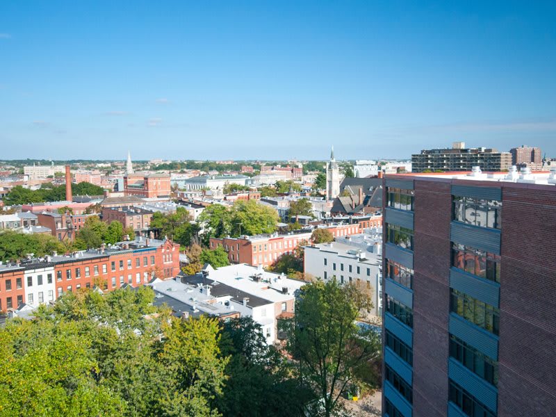 Aerial view of an urban cityscape with buildings and trees under a clear blue sky.