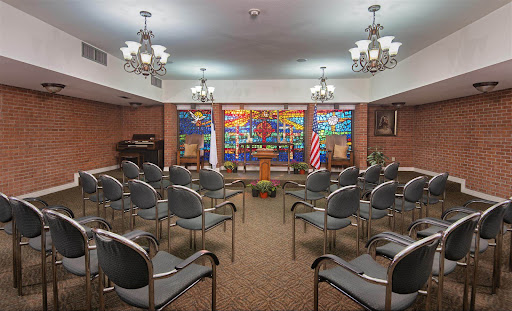 A room set up with chairs for an event, featuring colorful artwork and national flags.