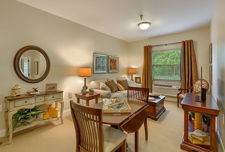 A cozy living room with a dining area, decorated with warm tones and elegant furniture.