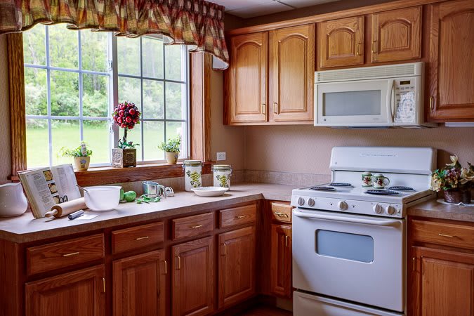 A cozy kitchen with wooden cabinets, a stove, and a window view.