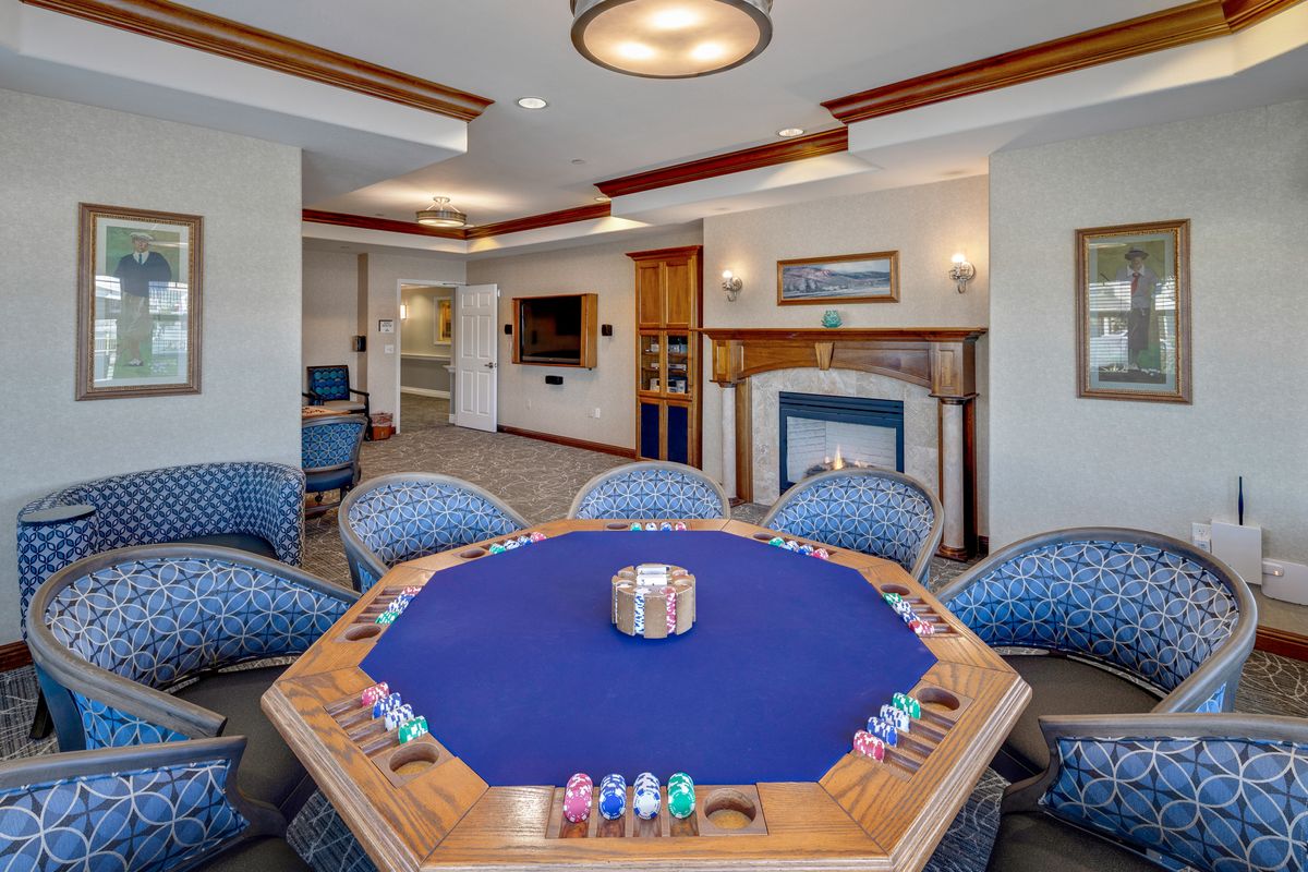 A luxurious game room featuring a poker table with chips and comfortable seating.