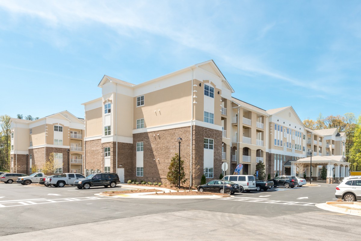 A modern hotel building with a parking lot on a clear day.
