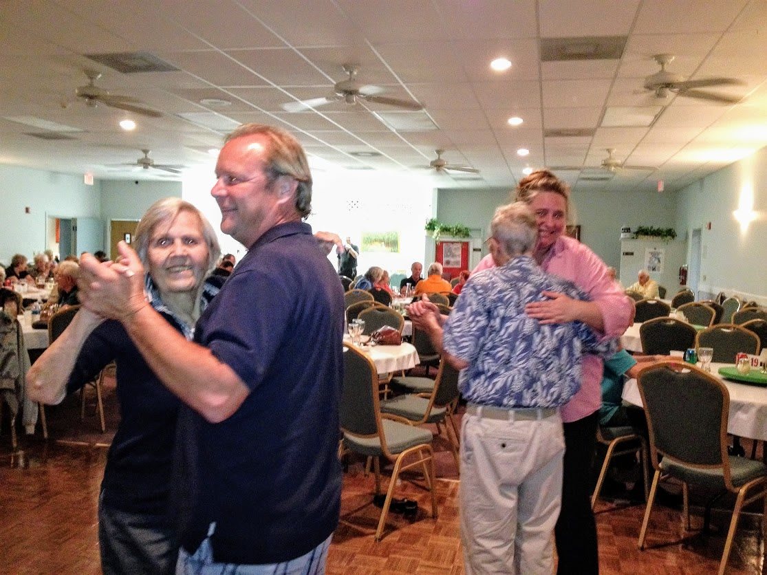 People dancing at a social event inside a venue.