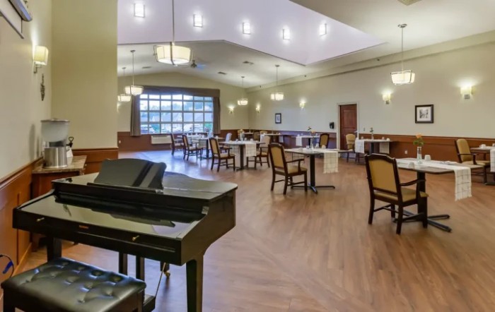 A spacious dining area with a piano, featuring wooden floors and elegant lighting.