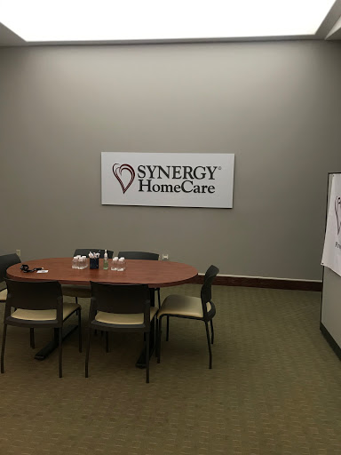 A meeting room setup featuring Synergy HomeCare branding.