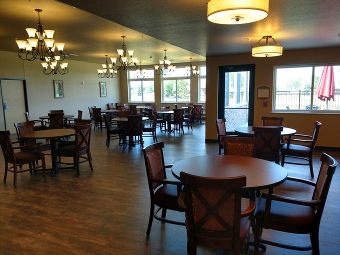 An empty dining area featuring wooden tables and chairs with elegant lighting fixtures.