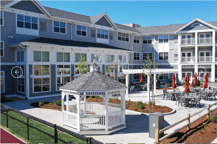 A modern residential building with a landscaped courtyard featuring a white gazebo.