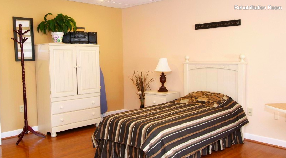 A cozy bedroom with a striped bedspread, white furniture, and a decorative lamp.