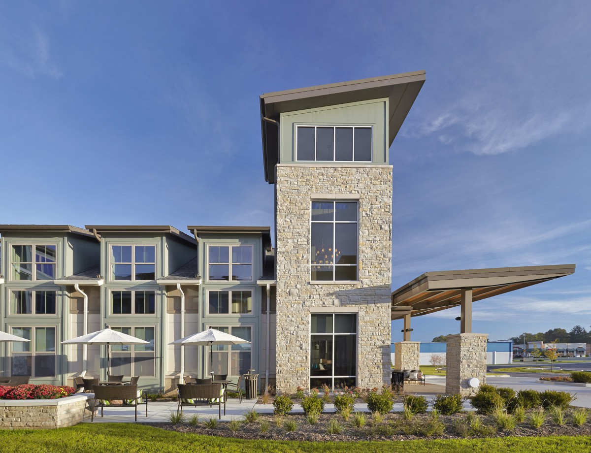 A modern building with a stone facade and outdoor seating area under a clear blue sky.