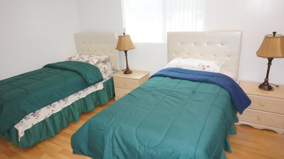 A cozy bedroom with two twin beds and a nightstand with a lamp.