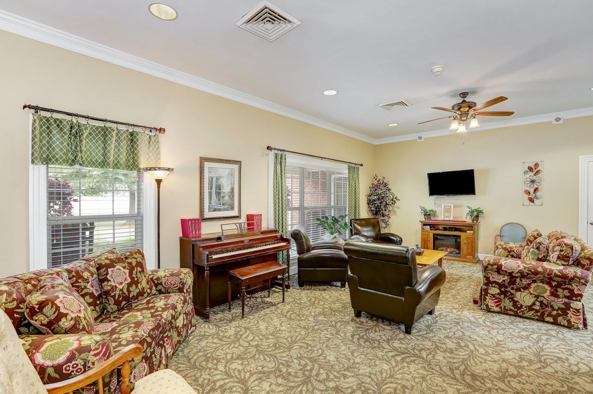 A cozy living room featuring a piano, comfortable seating, and a television.
