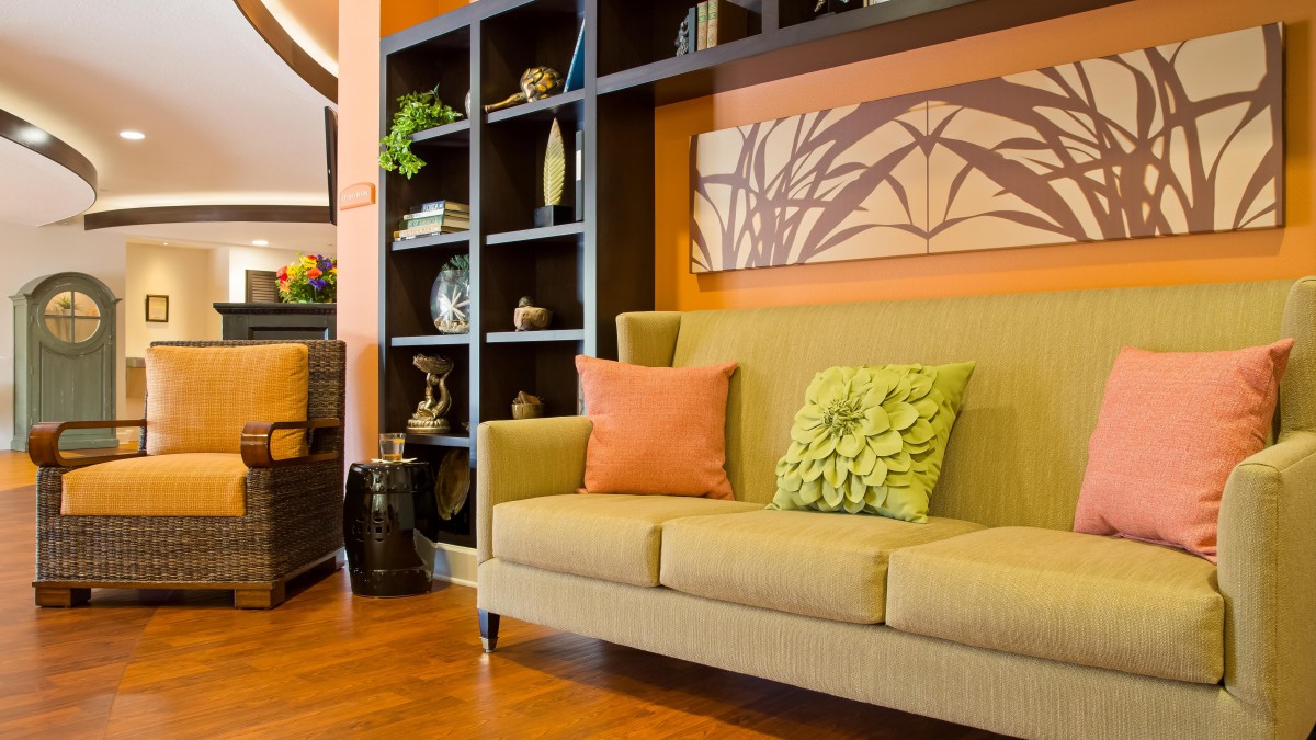 A modern living room with a stylish sofa, decorative pillows, and shelves filled with ornaments.