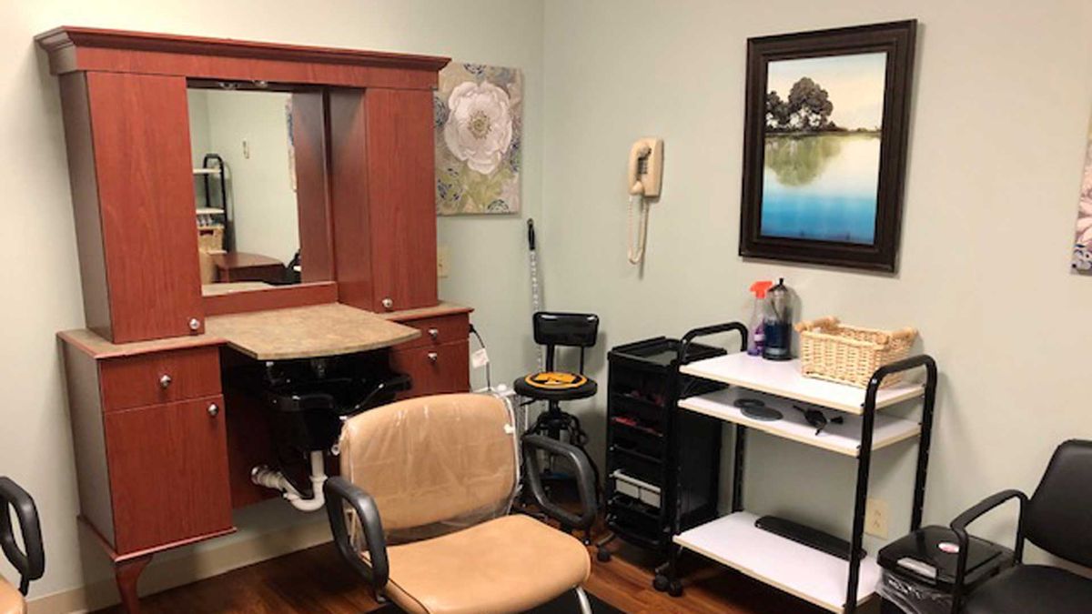 A cozy hair salon interior with a styling chair, mirror, and equipment.