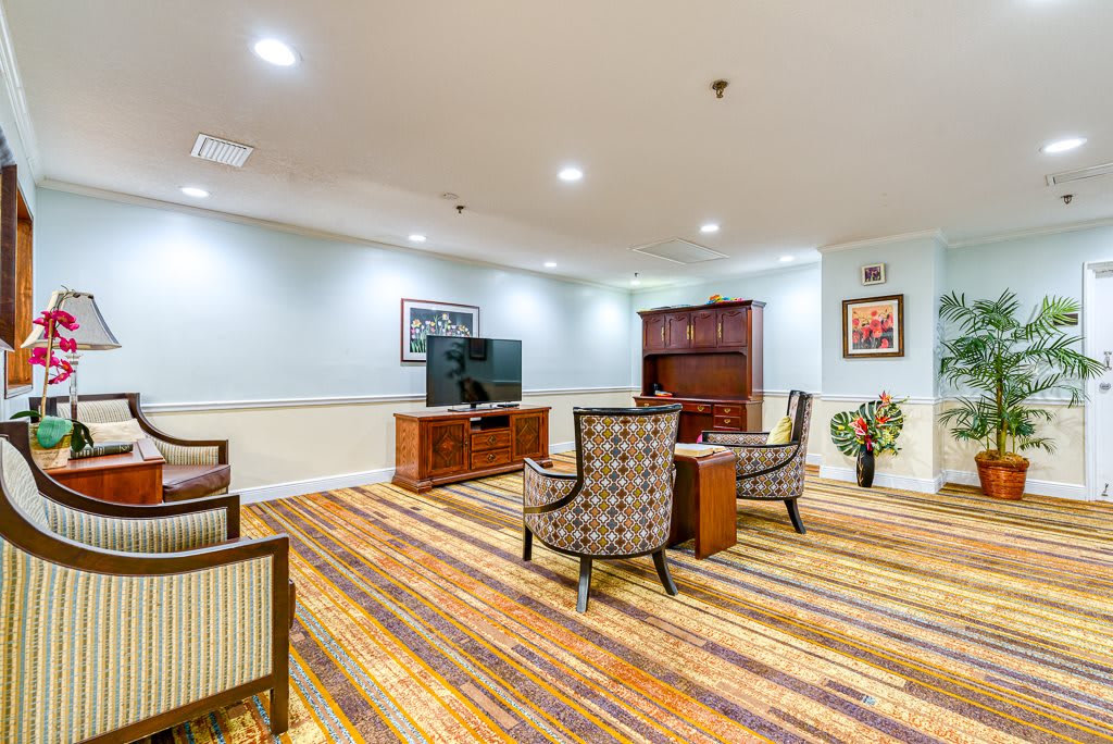 A cozy living room with a television, patterned carpet, and comfortable seating.