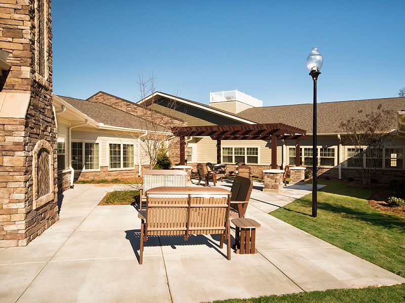 A sunny outdoor patio area with seating and a view of a building in the background.
