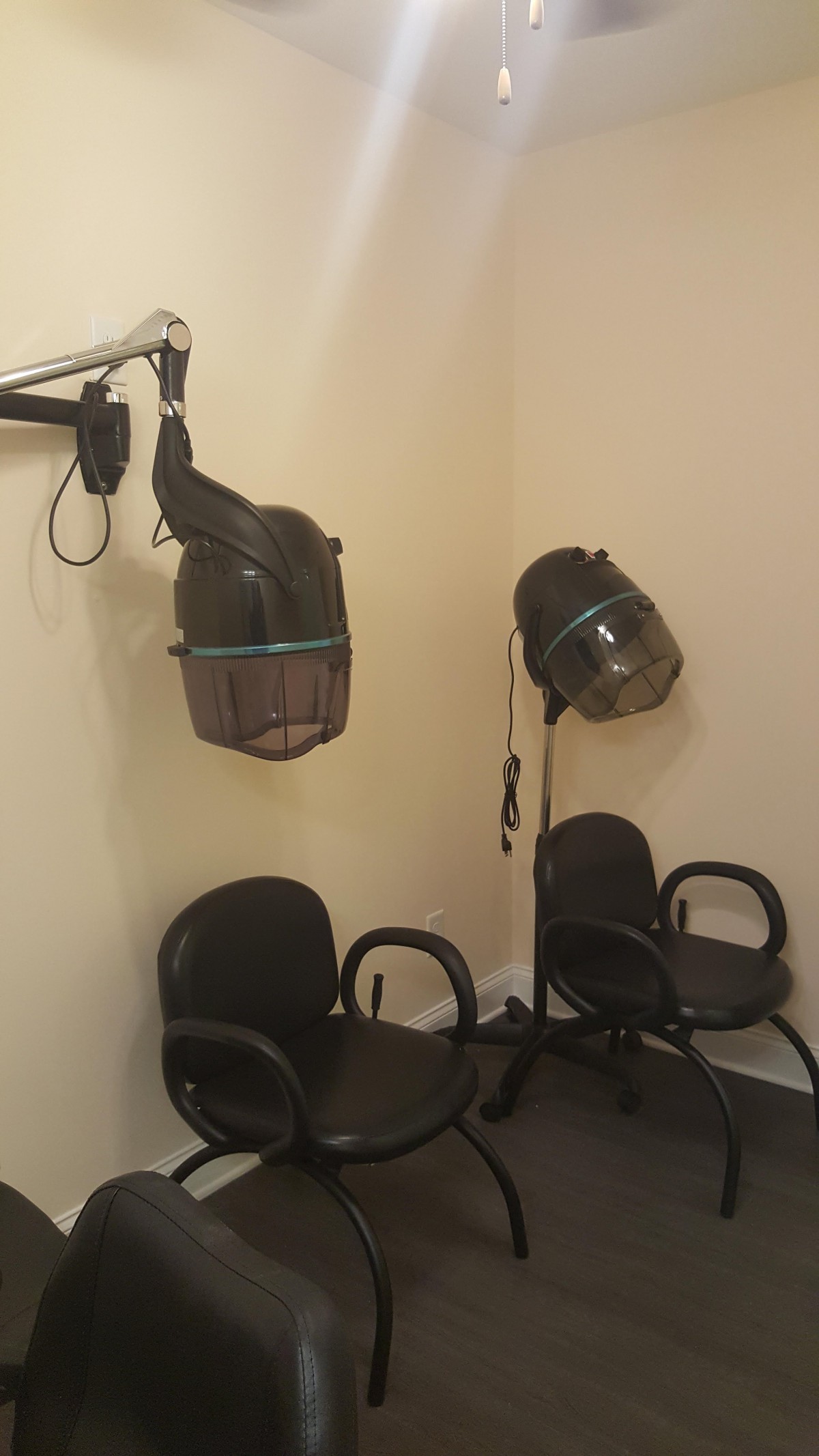 A hair salon corner with two vintage hair dryers and chairs.