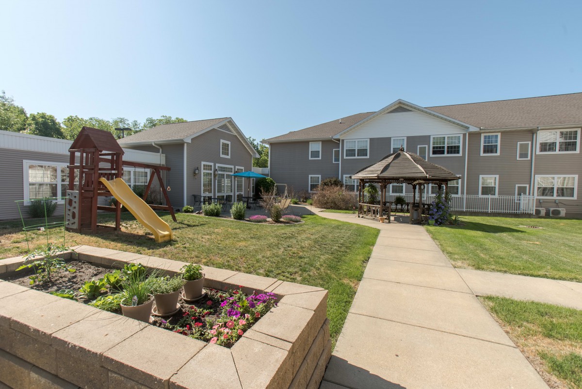 Apartment complex courtyard featuring a playground, gazebo, and garden.