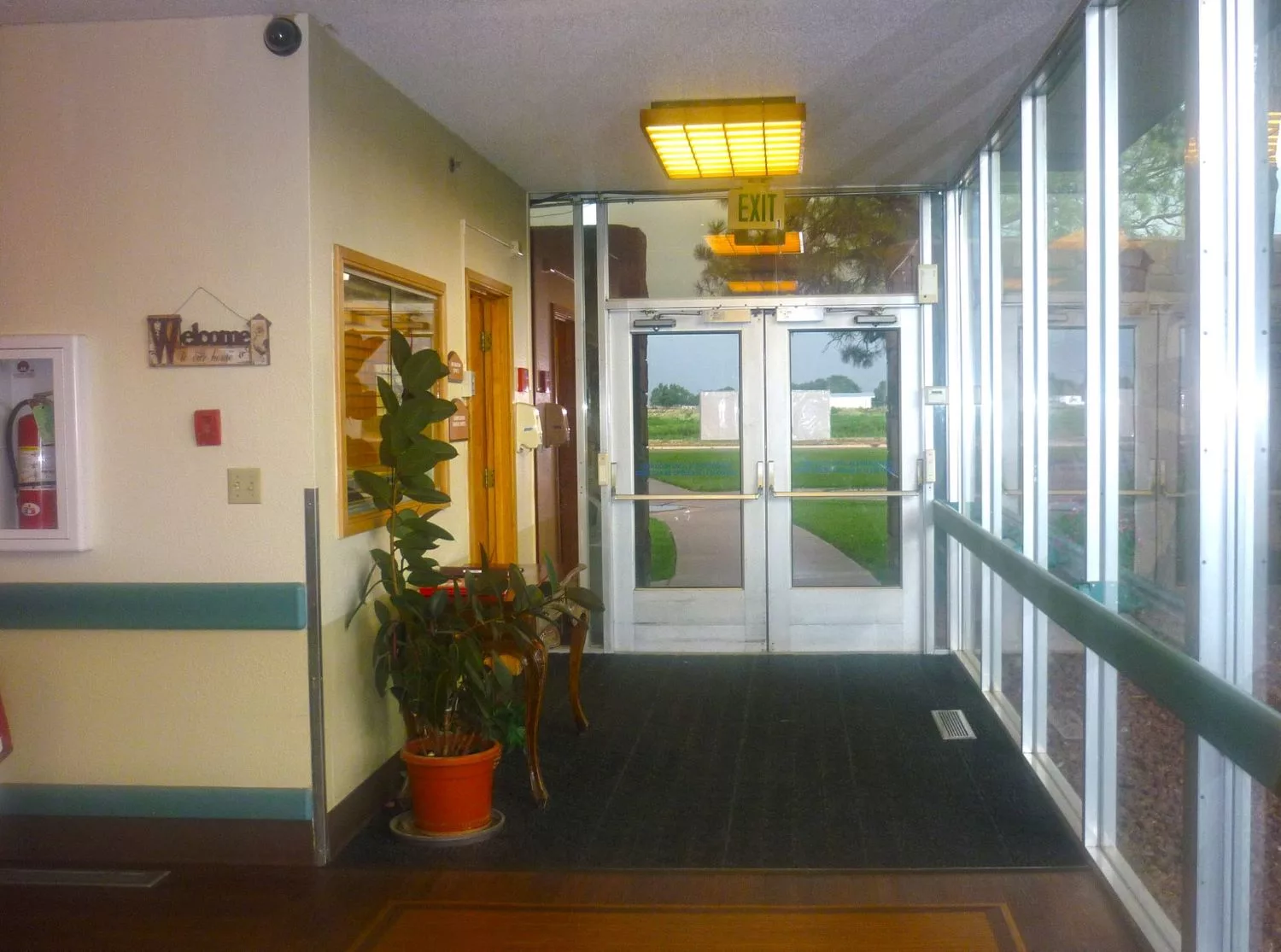 A hallway with potted plants leading to a set of glass doors.