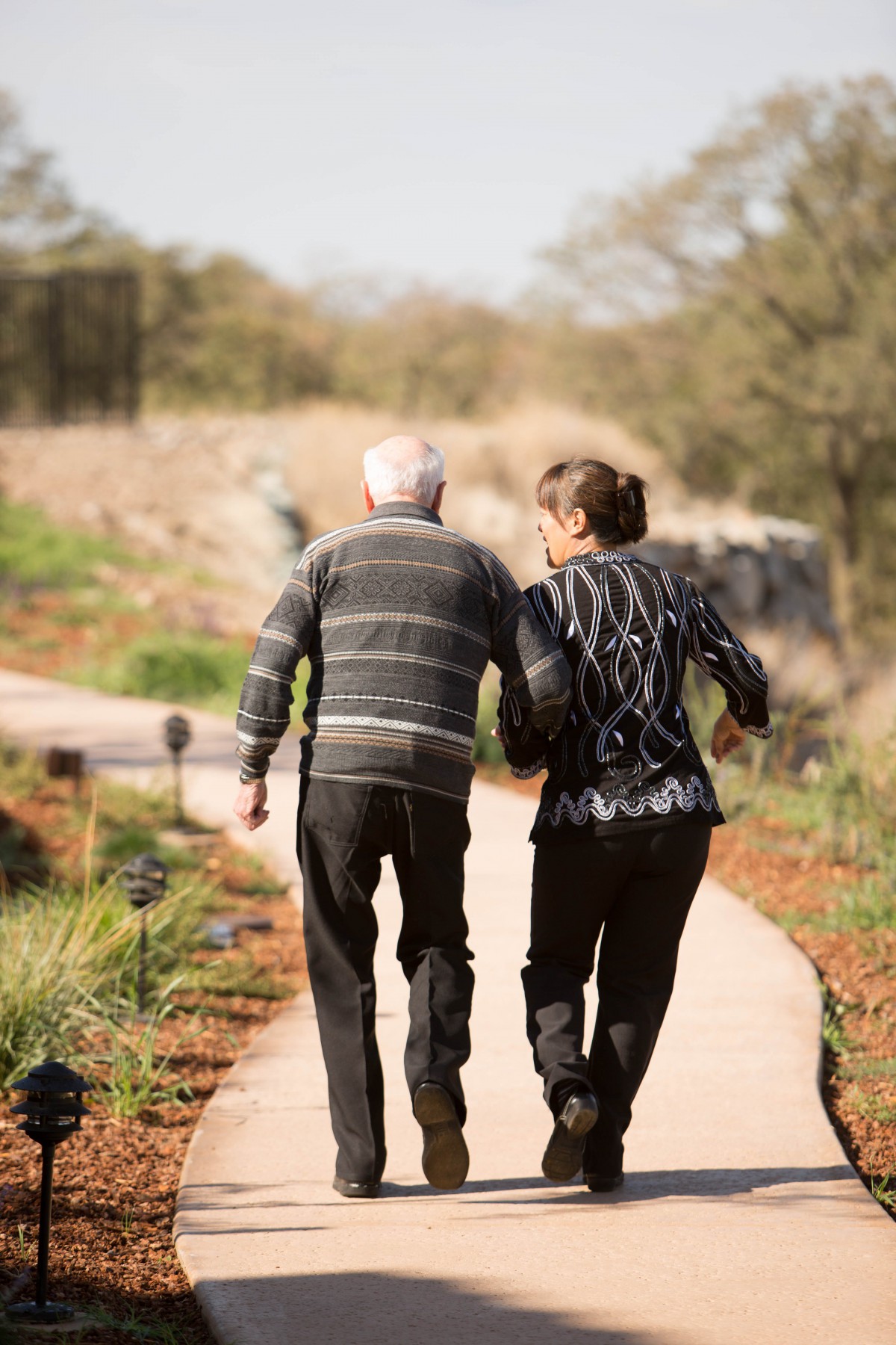 An elderly couple walking together along a scenic pathway.