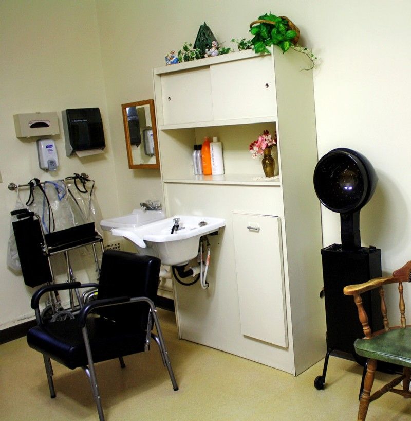 A small hair salon setup with a chair, sink, and hair drying equipment.