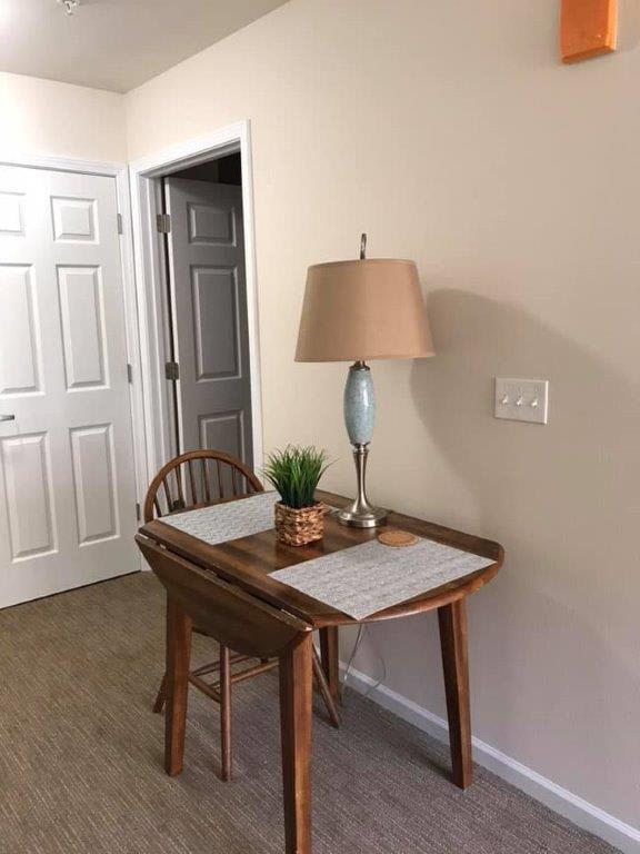 A cozy corner with a small desk, lamp, and chair.