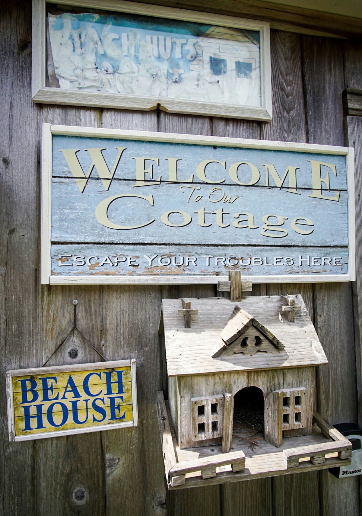Rustic welcome signs at a cottage entrance featuring beach house decor.