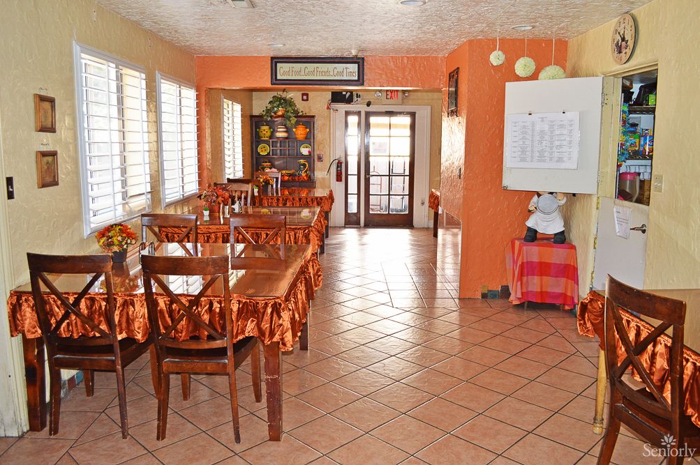 A cozy restaurant dining area with orange walls and neatly arranged tables and chairs.