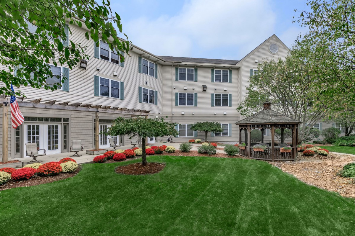 A peaceful residential garden with a gazebo and manicured lawn.