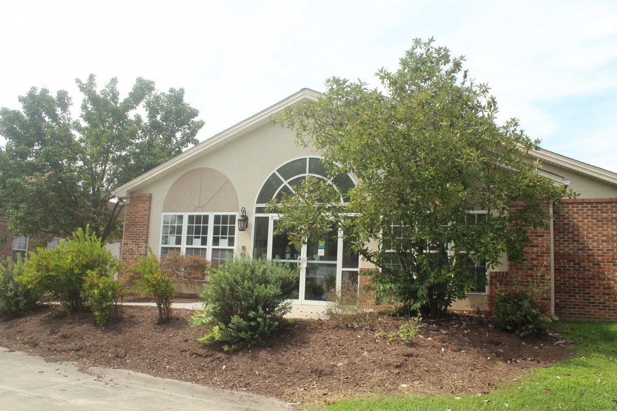 A well-landscaped residential house with large windows and brick exterior.