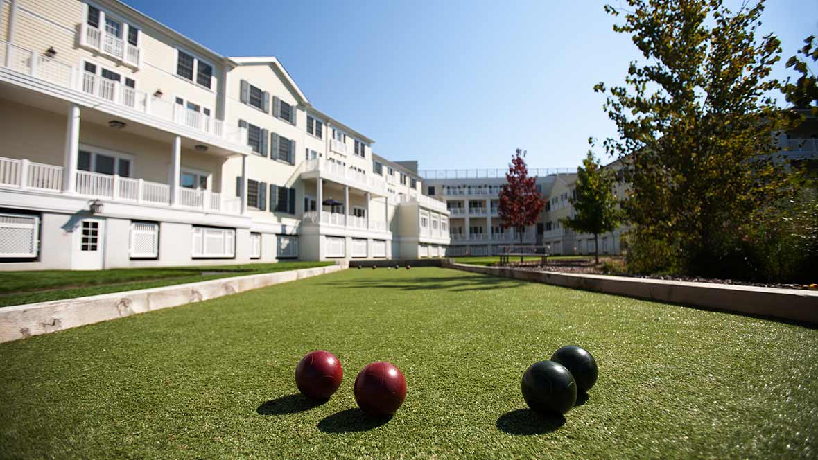 A lawn with bocce balls in front of a residential building complex on a sunny day.