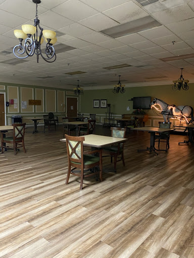 An empty recreational space featuring tables and chairs with wooden flooring.
