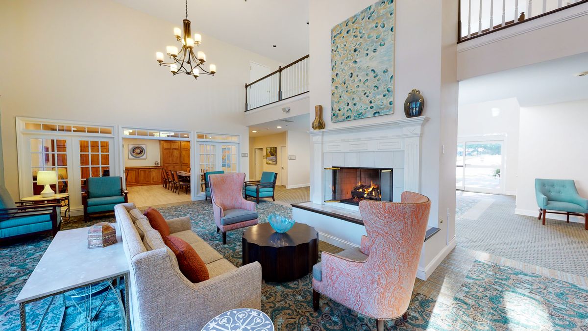 A spacious and elegantly designed living room featuring a cozy fireplace, plush furniture, and modern artwork.