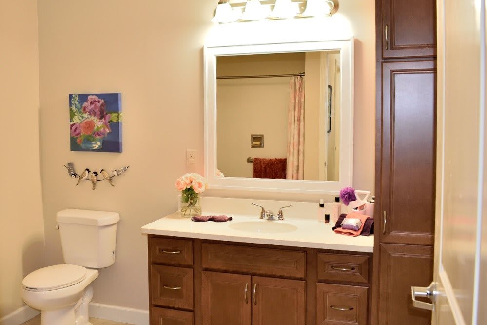 A well-lit bathroom with a sink, mirror, and wooden vanity.