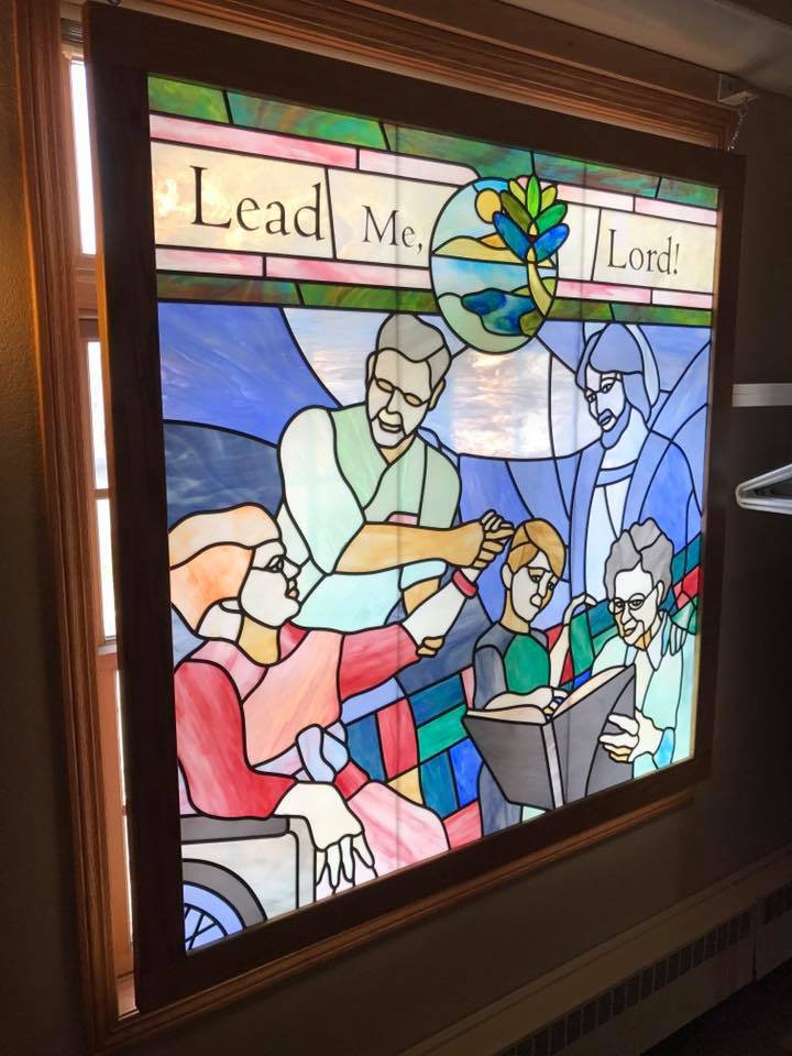 A stained glass window depicting a religious scene with the text 'Lead Me, Lord'.