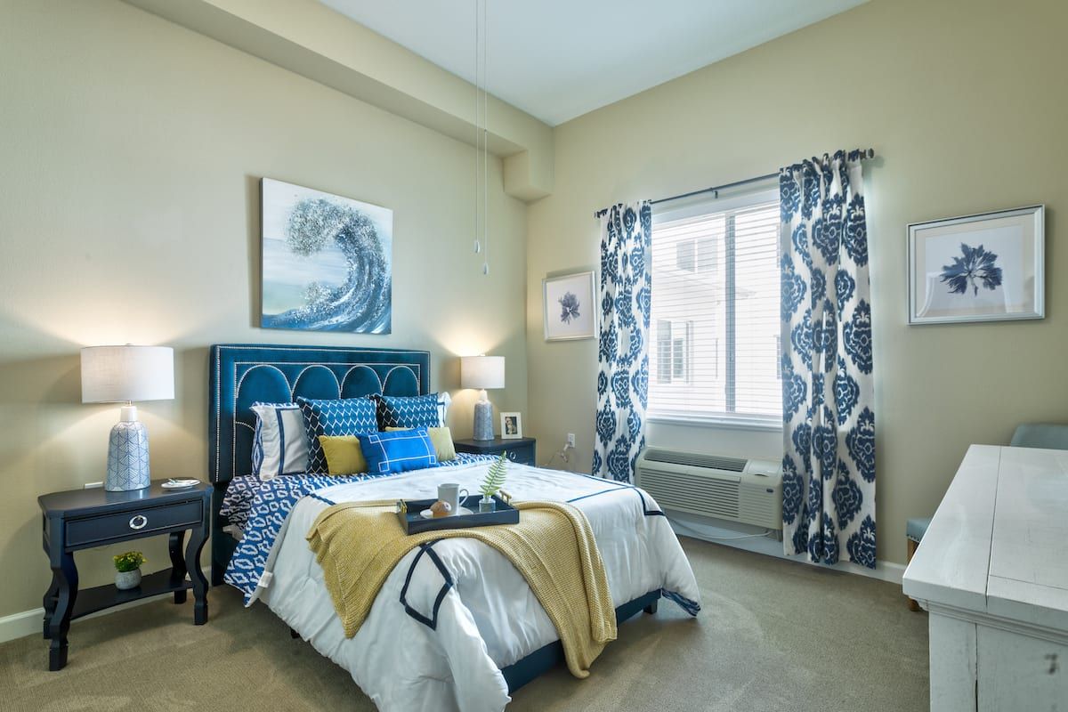 A modern bedroom with blue and yellow accents, featuring stylish decor and ample natural light.