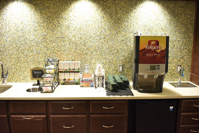 A well-organized coffee station with a beverage dispenser and condiments on a countertop.