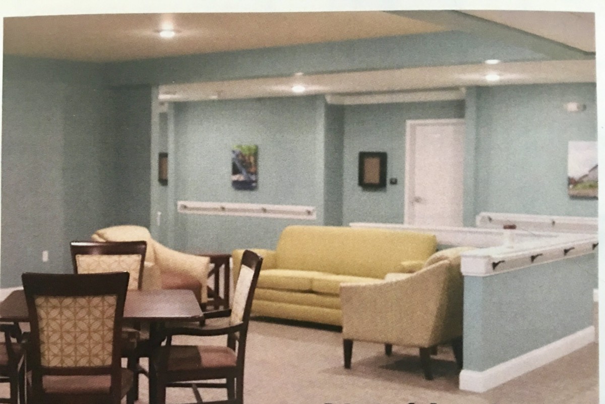 A cozy living room with a sofa, armchair, and dining table set against light blue walls.
