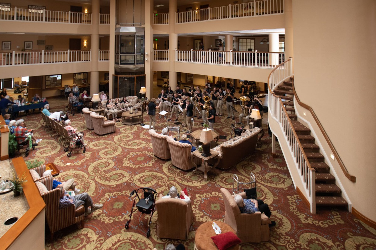 A spacious lobby with multiple seating areas, where a group of seniors are gathered, creating a warm and social atmosphere.