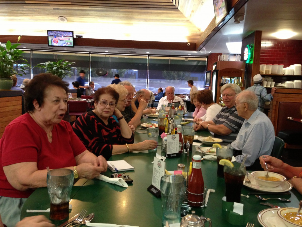 A group of people gathered around a restaurant table, enjoying a meal and conversation.