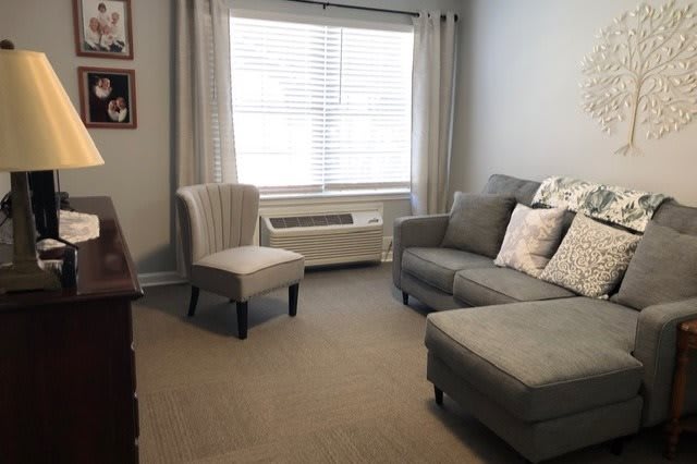 A cozy living room with a sofa, chair, and large window.