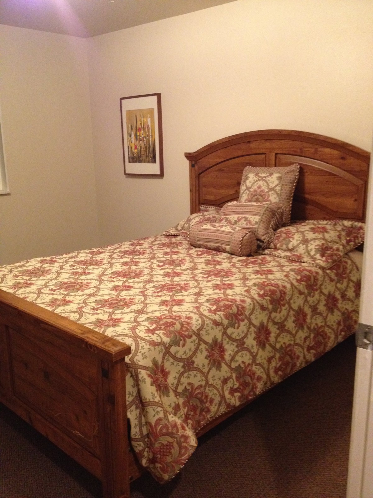A cozy bedroom with a wooden bed and floral patterned quilt.