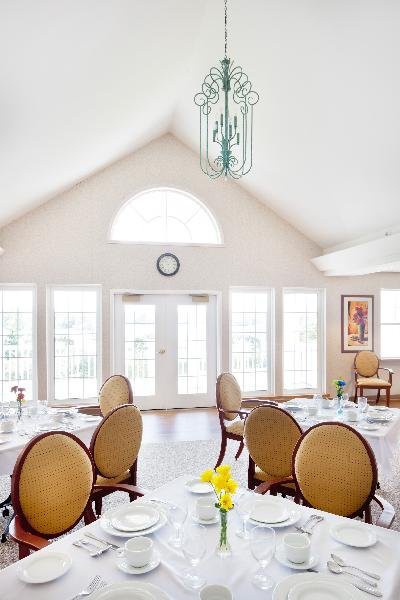 A bright dining room with elegantly set tables and large windows.