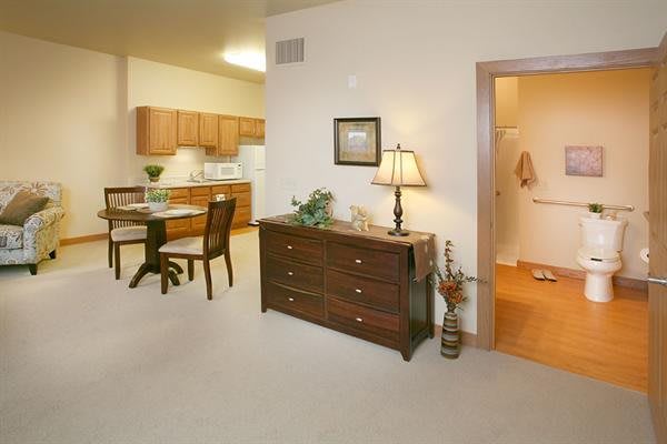 A cozy apartment interior featuring a dining area and kitchen with wooden cabinets and furniture.
