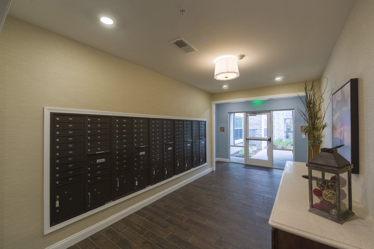 A well-lit apartment mailroom with multiple mailboxes and an entrance door.