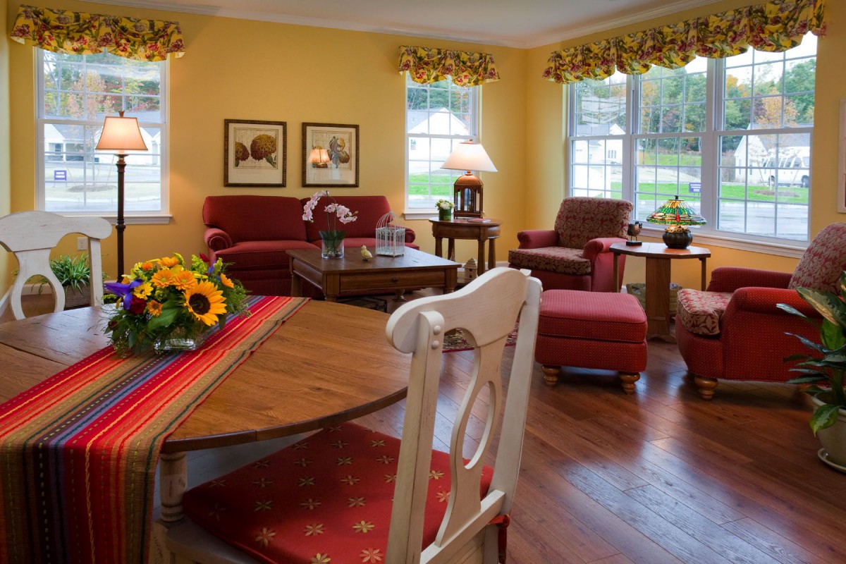 A cozy living room with traditional decor, featuring red sofas, yellow walls, and wooden furniture.