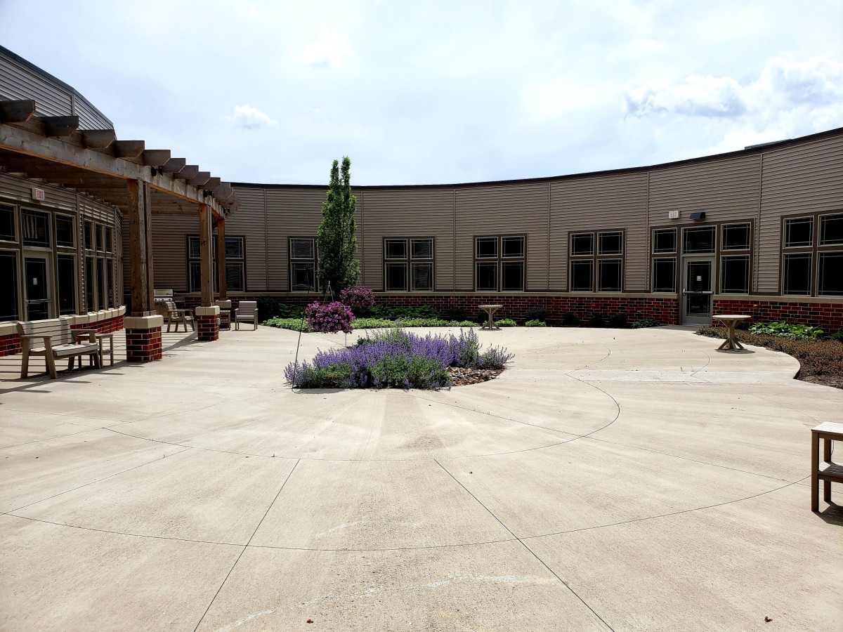 A courtyard featuring a central garden with flowers, surrounded by a building with multiple windows.