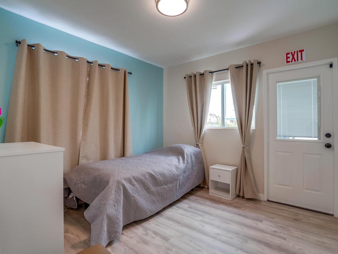 A minimalist bedroom with a single bed and light decor.
